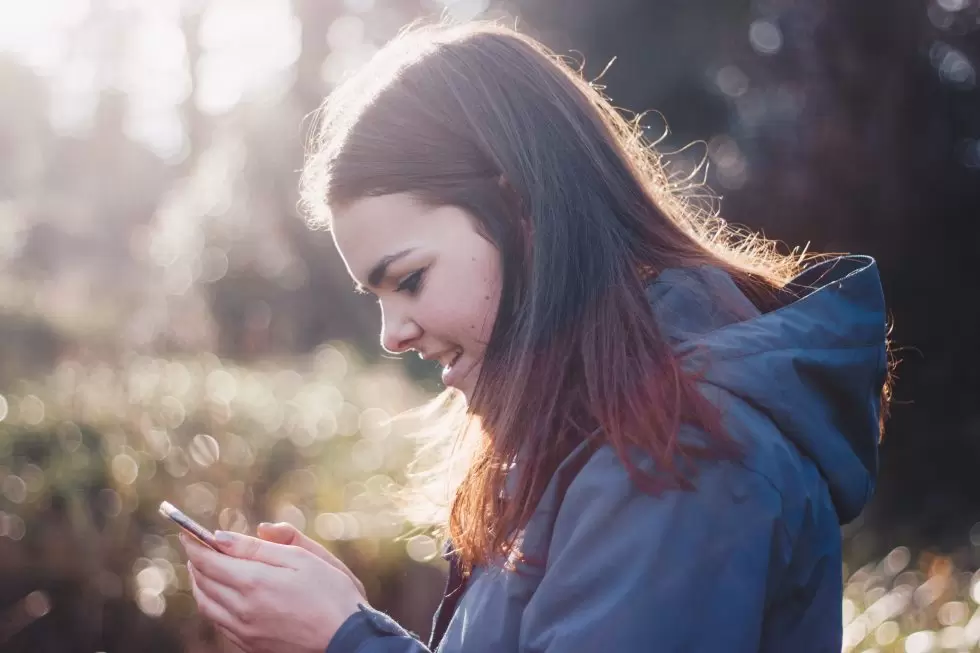 teen outdoors texting on cell phone